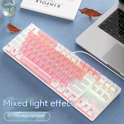 Mechanical keyboard with colorful backlighting on a blue surface next to a laptop.